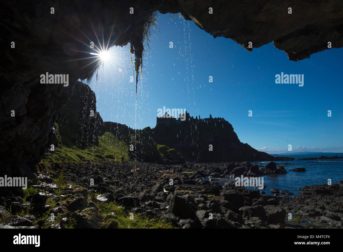 Silhouette di Dunluce Castle dall'interno di una grotta marina, Causeway Coast, County Antrim, Irlanda del Nord. Foto Stock