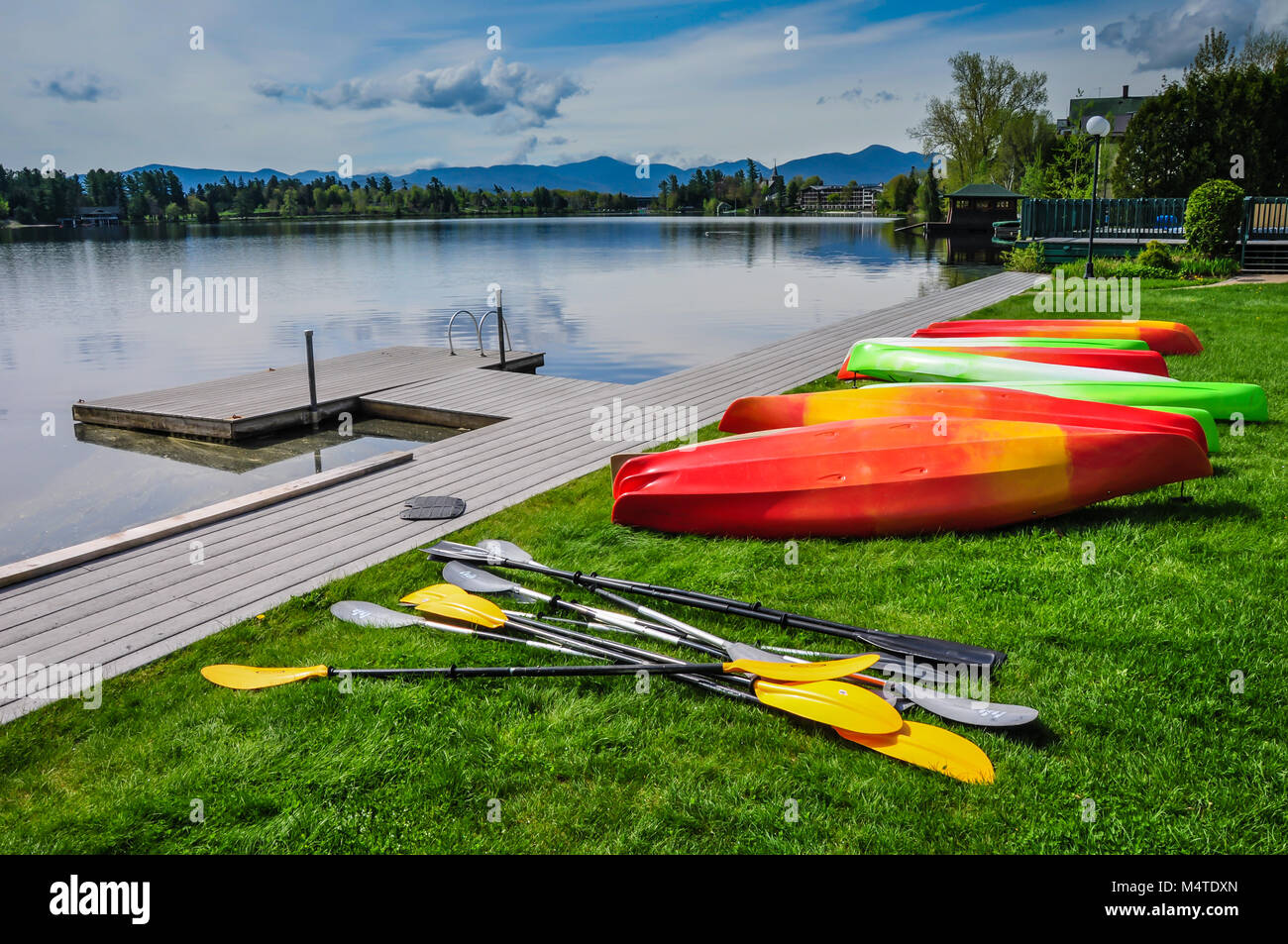 Fila di kayak e pagaie in attesa sul dock di Mirror Lake in Lake Placid, New York, Stati Uniti d'America. Foto Stock