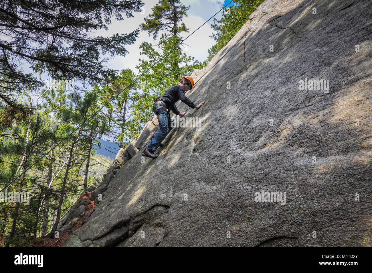 Ragazzo giovane arrampicata roccia nelle Montagne Adirondack di Upstate New York. Foto Stock