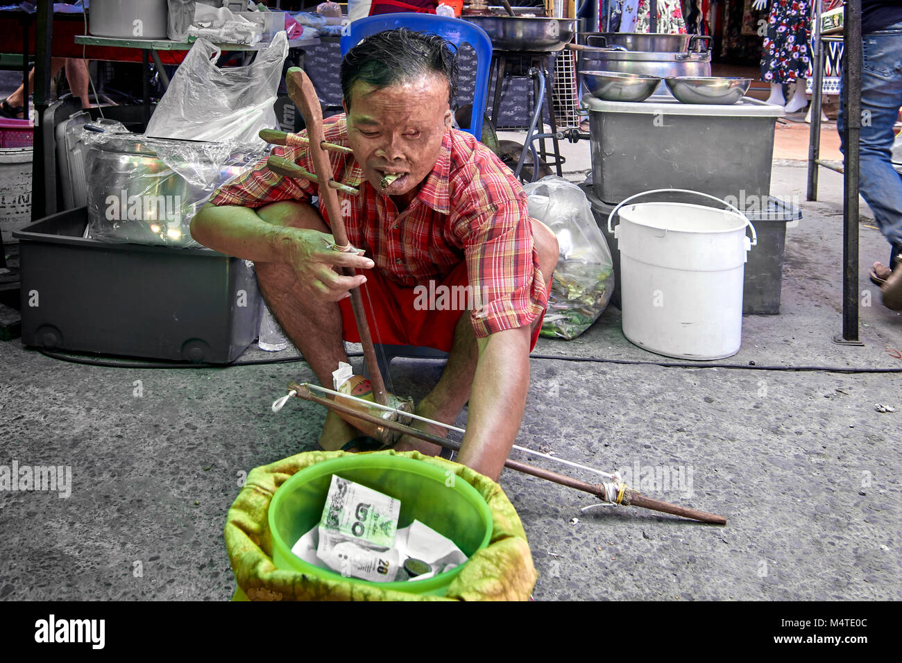 Sfigurato uomo con ustioni del viso la riproduzione di musica di strada per reddito. Thailandia del sud-est asiatico Foto Stock
