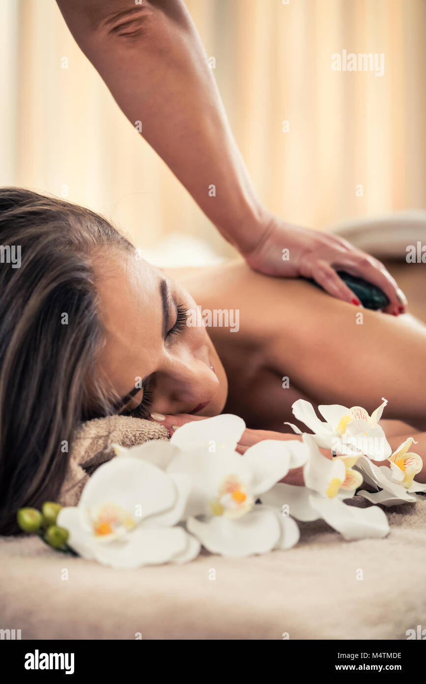 Donna godendo gli effetti terapeutici di un tradizionale massaggio hot stone Foto Stock