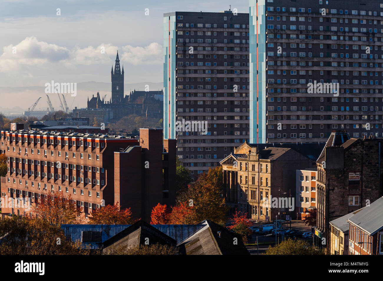 Vista dello skyline di Glasgow che si affaccia sull'alloggiamento sociale verso il campanile dell'Università di Glasgow con gru dei cantieri sullo sfondo, Scozia, Regno Unito Foto Stock