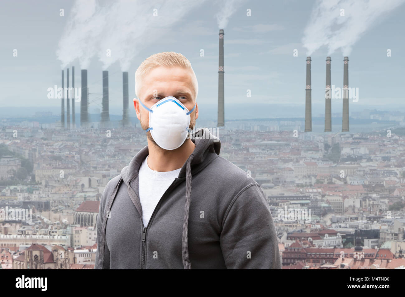 Un uomo che indossa la maschera di inquinamento contro l emissione di fumi da ciminiere Foto Stock
