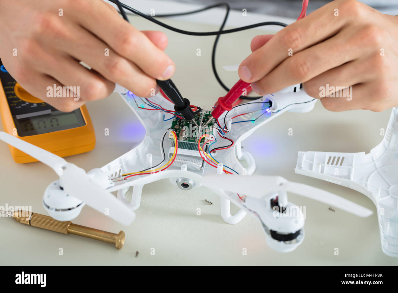 Close-up di un uomo prova corrente elettrica del Drone smontato utilizzando lo strumento del multimetro Foto Stock