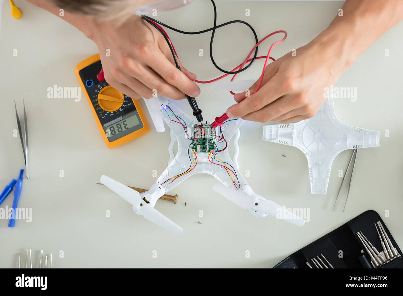 Close-up di un uomo prova corrente elettrica del Drone smontato utilizzando lo strumento del multimetro Foto Stock