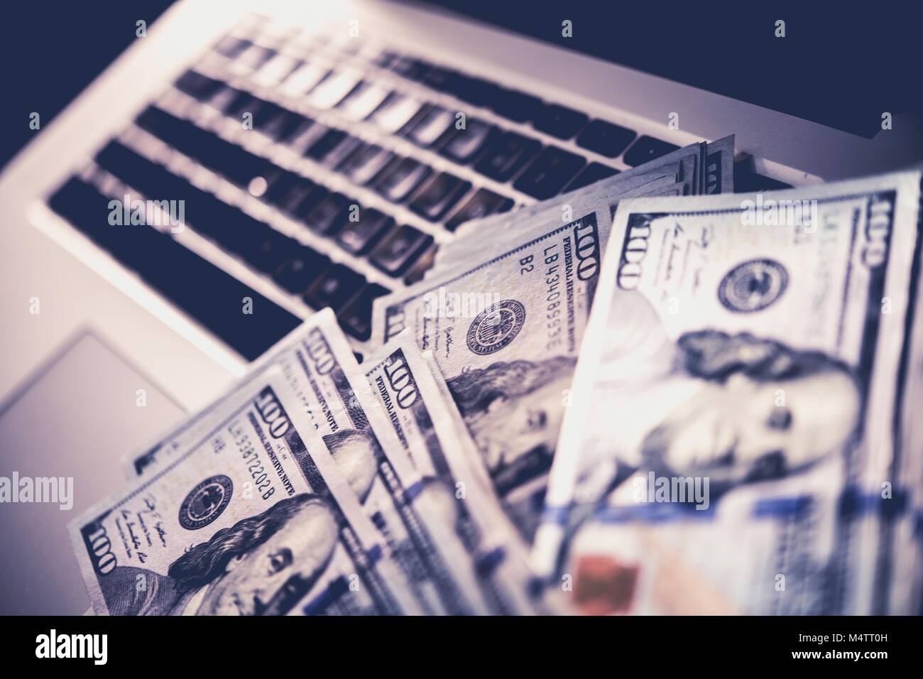 Truffa Internet denaro. Dollari guadagnati dalla criminalità informatica Foto concettuale con banconote posa sul computer portatile. Foto Stock