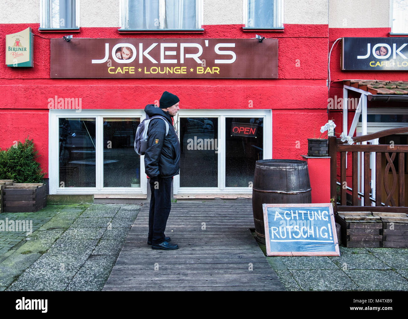 Berlin Pankow,Joker's Cafe Bar Lounge esterna e senior uomo anziano con zaino in spalla Foto Stock