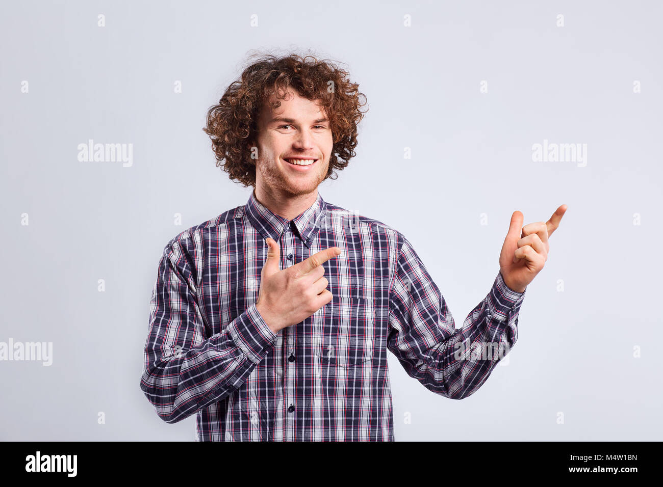 Curly ragazzo con emozione positiva sul suo volto a punti con la sua fing Foto Stock