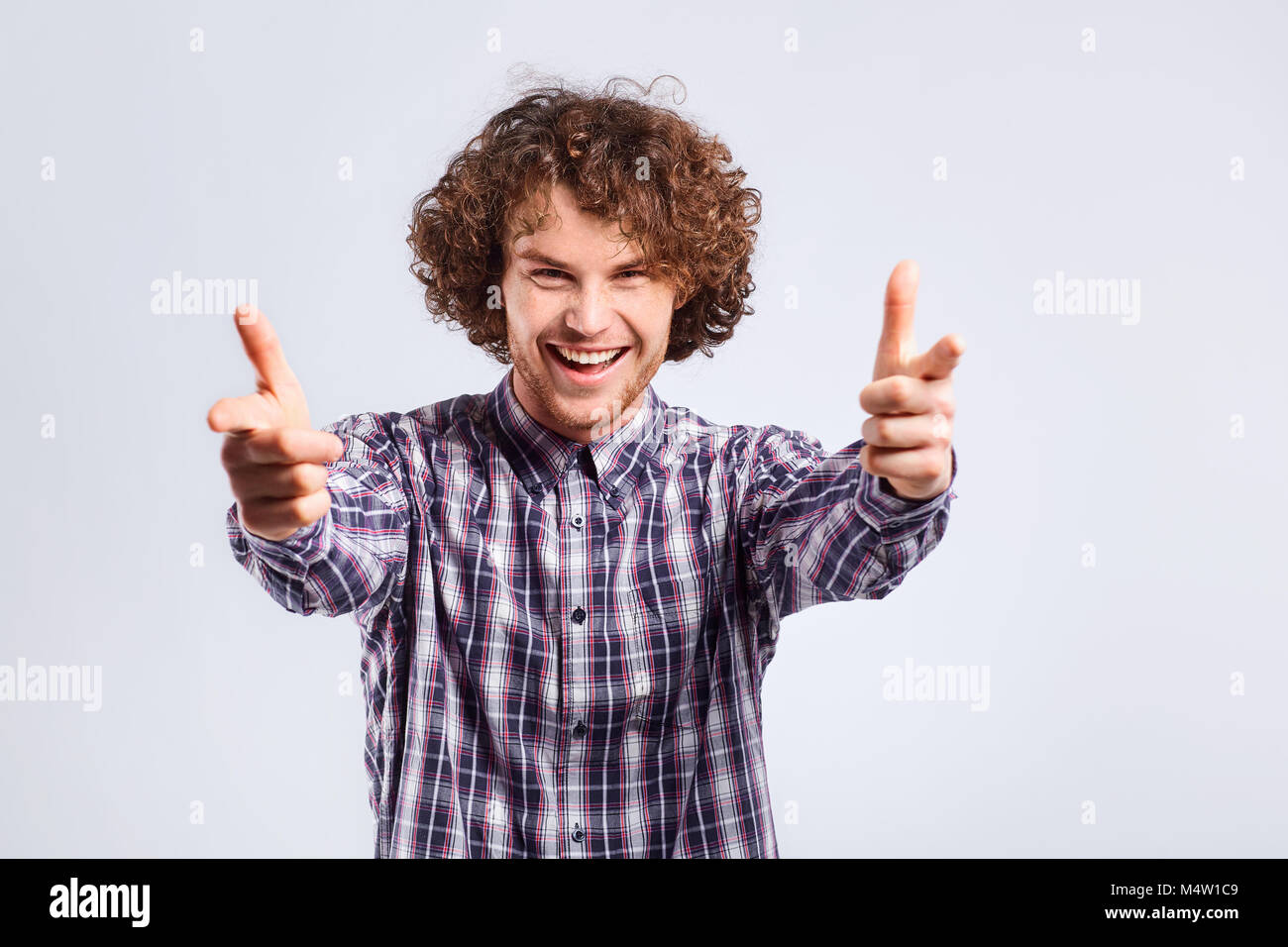 Un giovane curly-uomo dai capelli con un'emozione positiva punti proprio fing Foto Stock