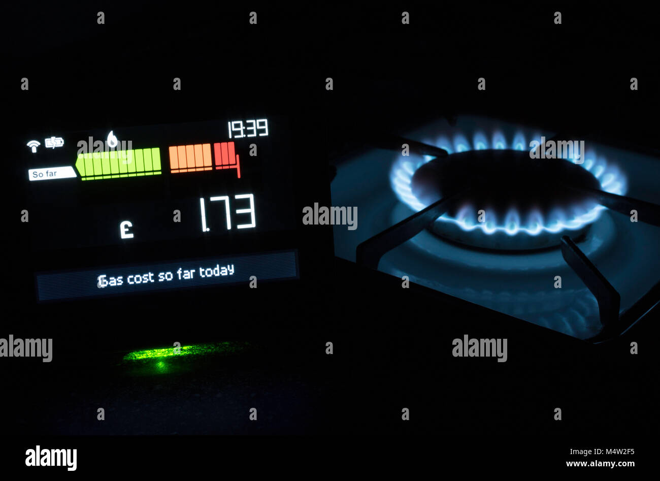 Tecnologia Chameleon Smart Meter mostra il costo del gas utilizzato oggi con piano cottura a gas in background, England, Regno Unito Foto Stock