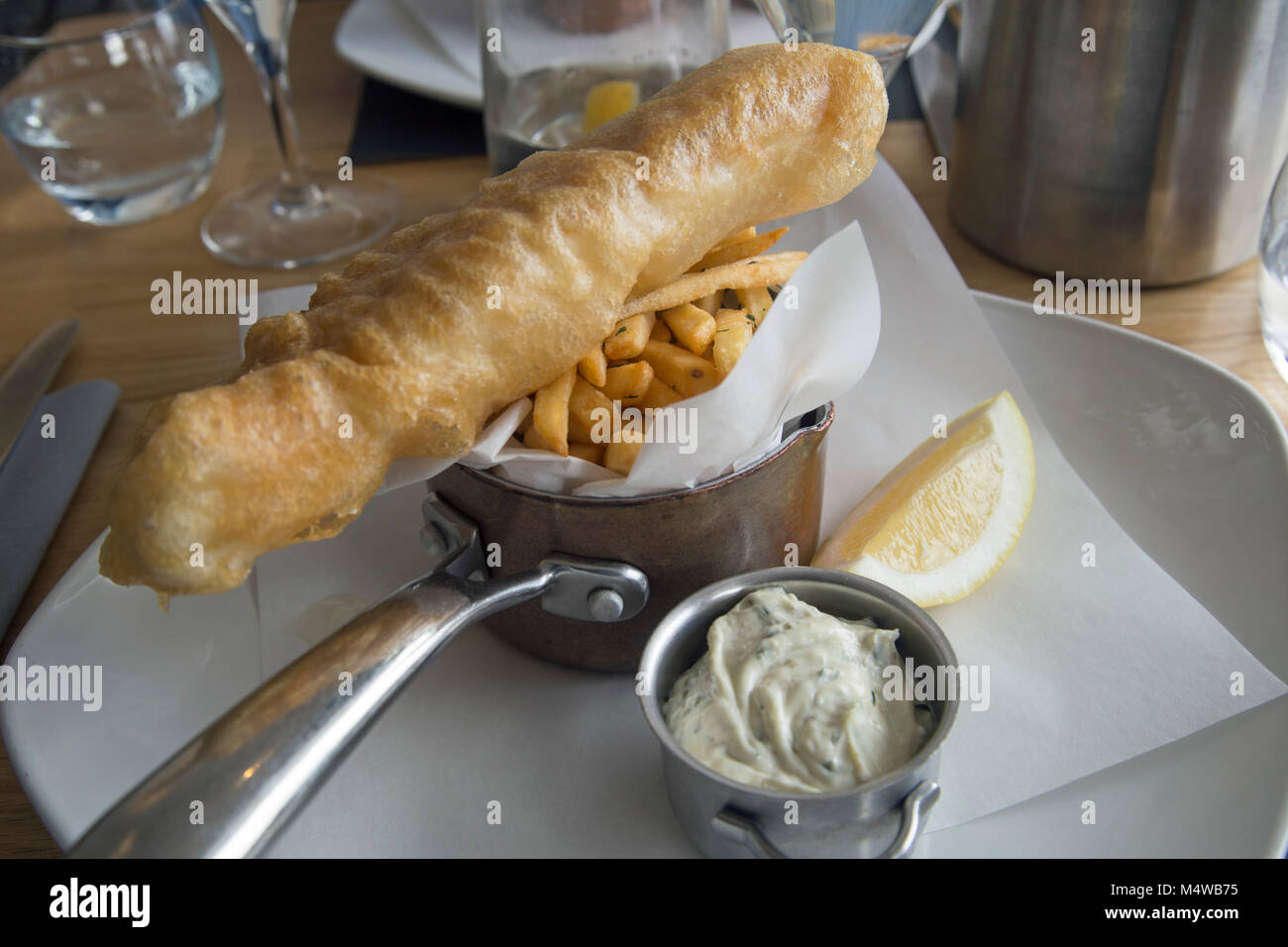 Pesce e patatine fritte servite con salsa di tartare e una fettina di limone Foto Stock