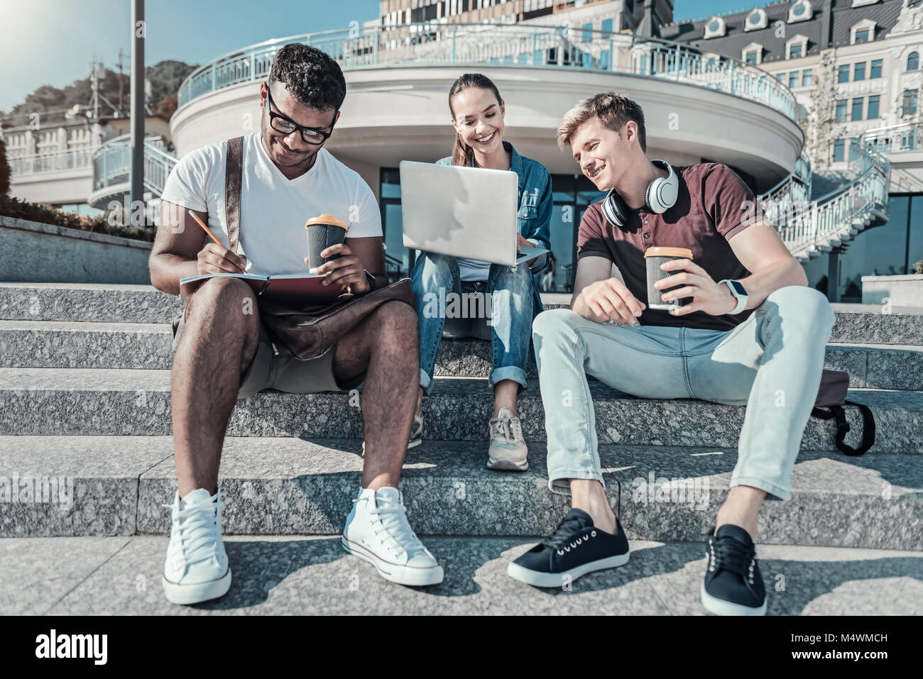 Bella felice gli studenti seduti sulle scale Foto Stock