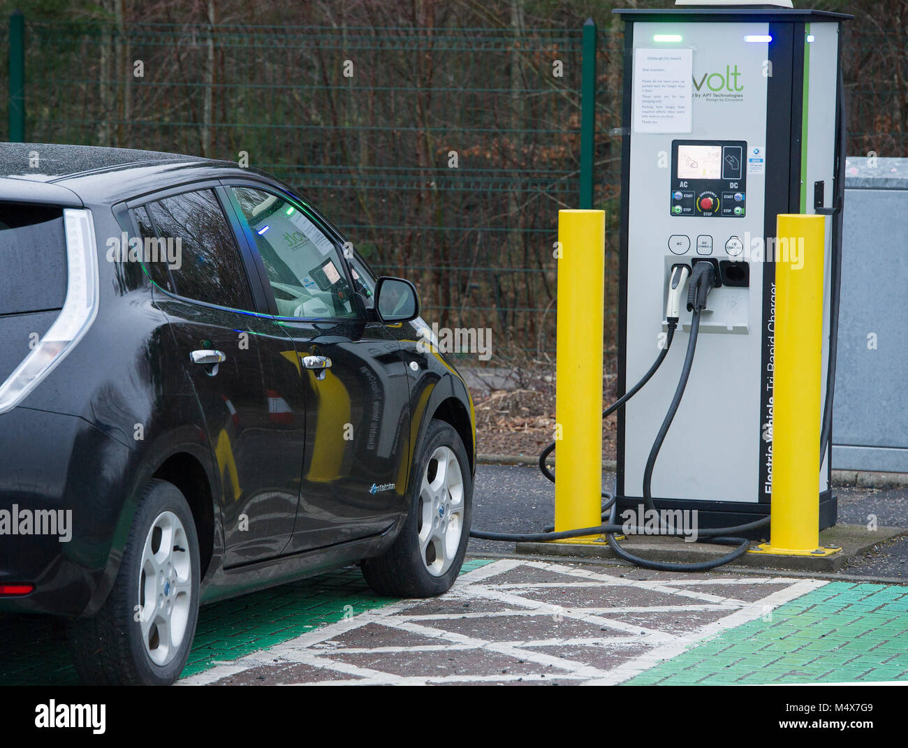 Una Nissan Leaf auto elettrica utilizzando un tri-caricabatteria rapido a un veicolo elettrico stazione di carica, Riccarton, Edimburgo. Foto Stock