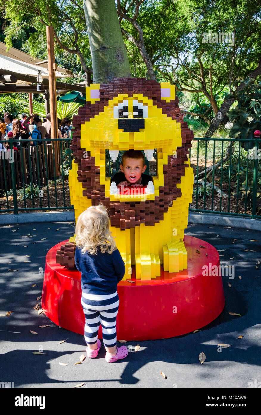 Carlsbad, CA, Stati Uniti d'America. Una bimba bionda guarda fino a un leone costruito in mattoncini Lego mentre un ragazzino ruggisce attraverso la bocca aperta. Foto Stock