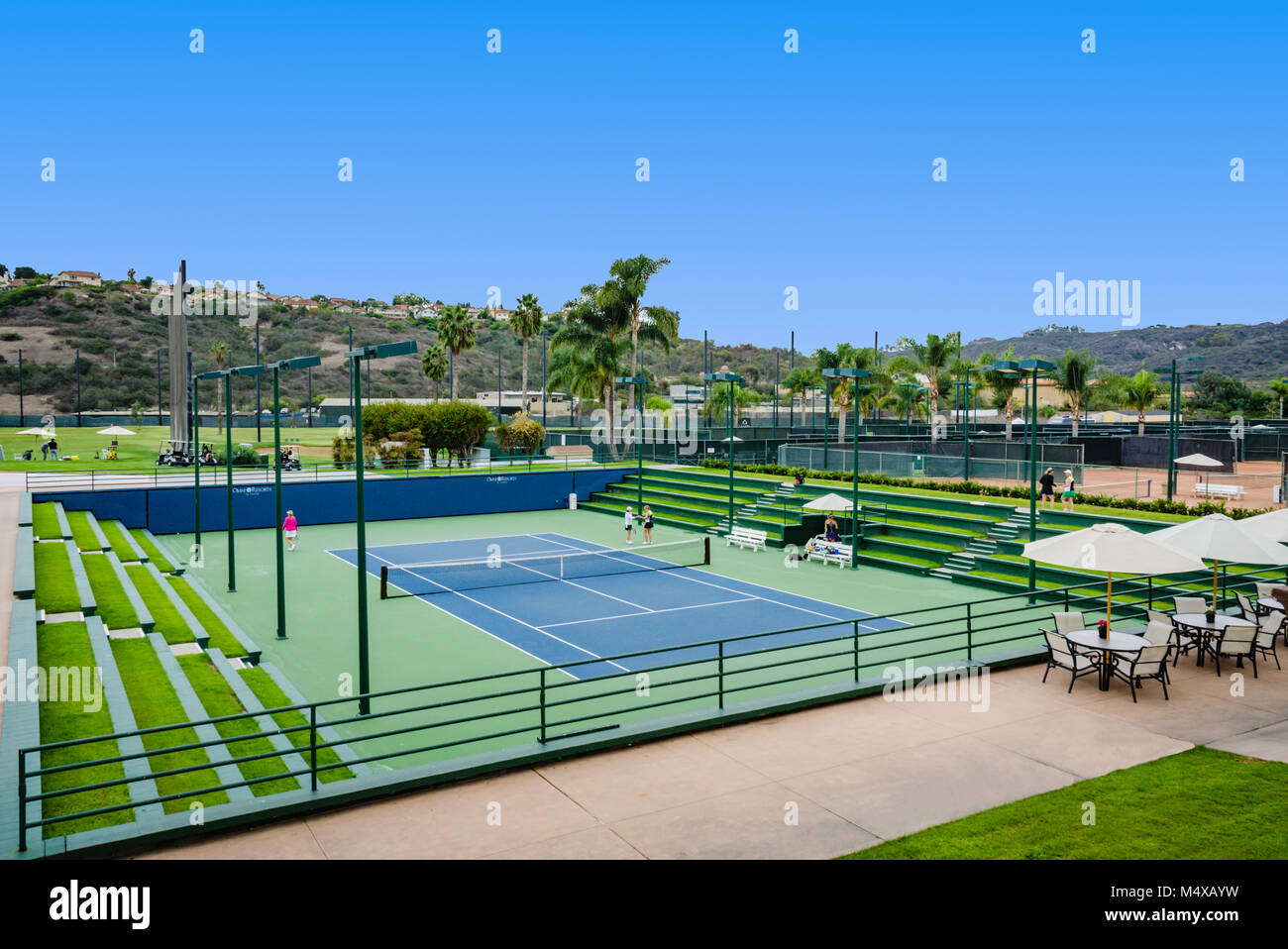 Carlsbad, CA, Stati Uniti d'America. Colore verde brillante campi da tennis con sedili dello stadio riempito con erba e un paio di spettatori. Foto Stock