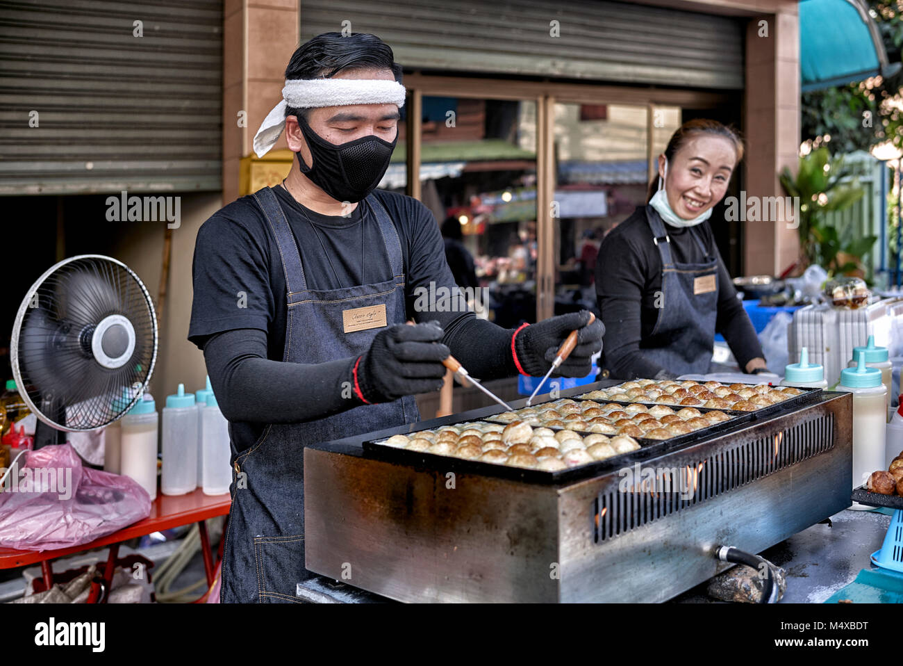 Chef che cucinano gnocchi giapponesi Takoyaki in un mercato di Street food all'aperto della Thailandia. Thailandia, S. E. Asia. Foto Stock