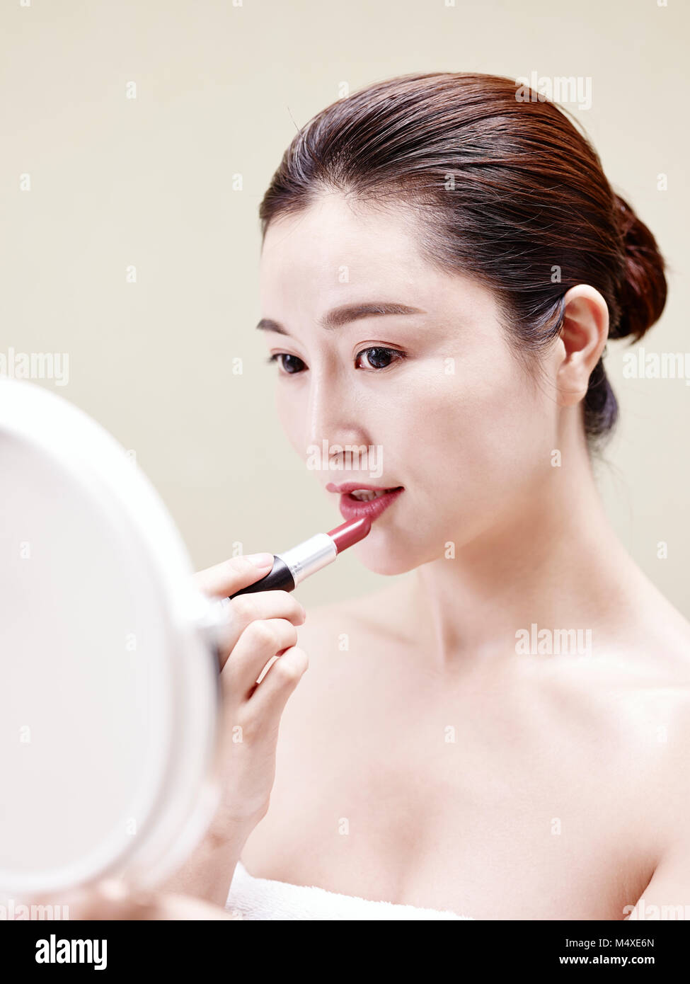 Bella giovane donna asiatica guardando nello specchio mentre il rossetto sulle labbra. Foto Stock