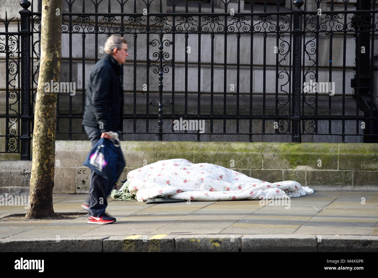 A piedi da persona senzatetto dormono per strada a Londra. Il fenomeno dei senzatetto. Passer ignorando traversina ruvida sulla fredda giornata invernale Foto Stock