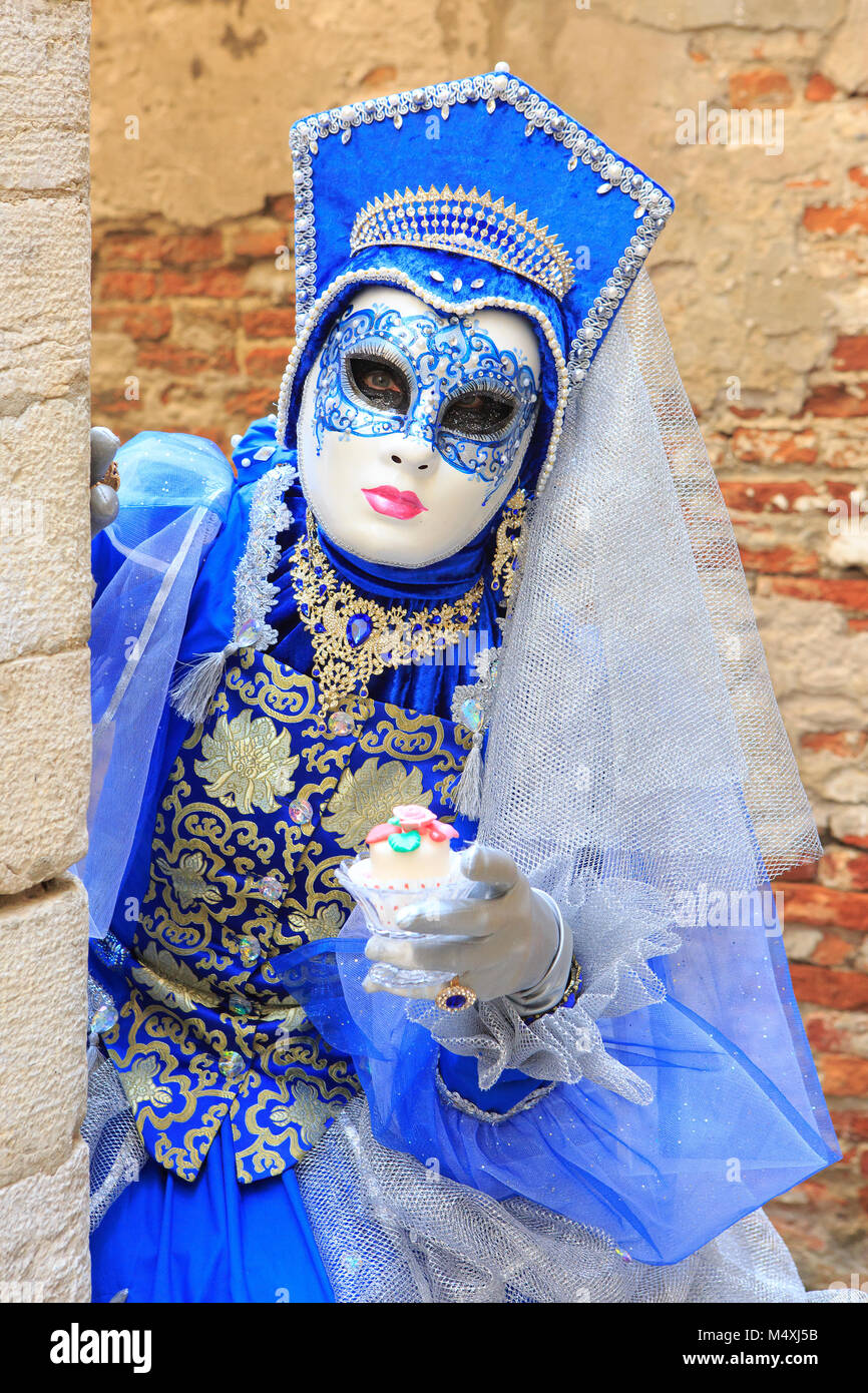Una donna mascherata in un vestito blu tenendo un cupcake durante il  Carnevale di Venezia (Carnevale di Venezia) a Venezia, Italia Foto stock -  Alamy