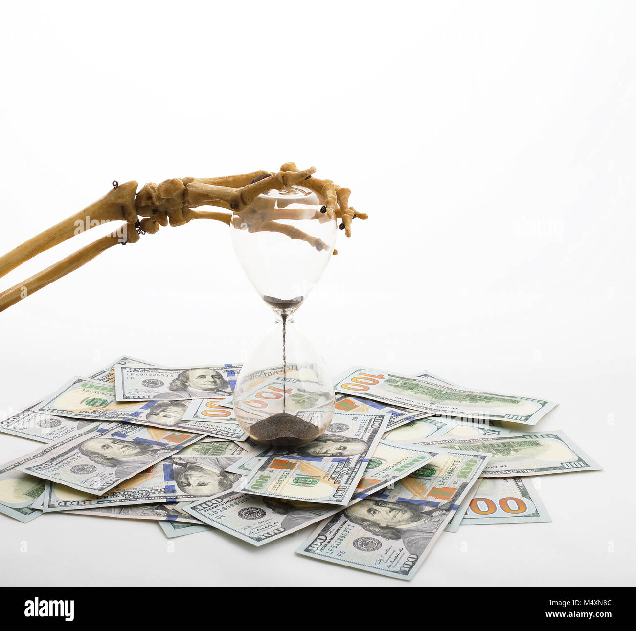 Dita di scheletro holding sabbia-vetro posto in dollari. concetto del tempo - il denaro e la morte. Foto Stock