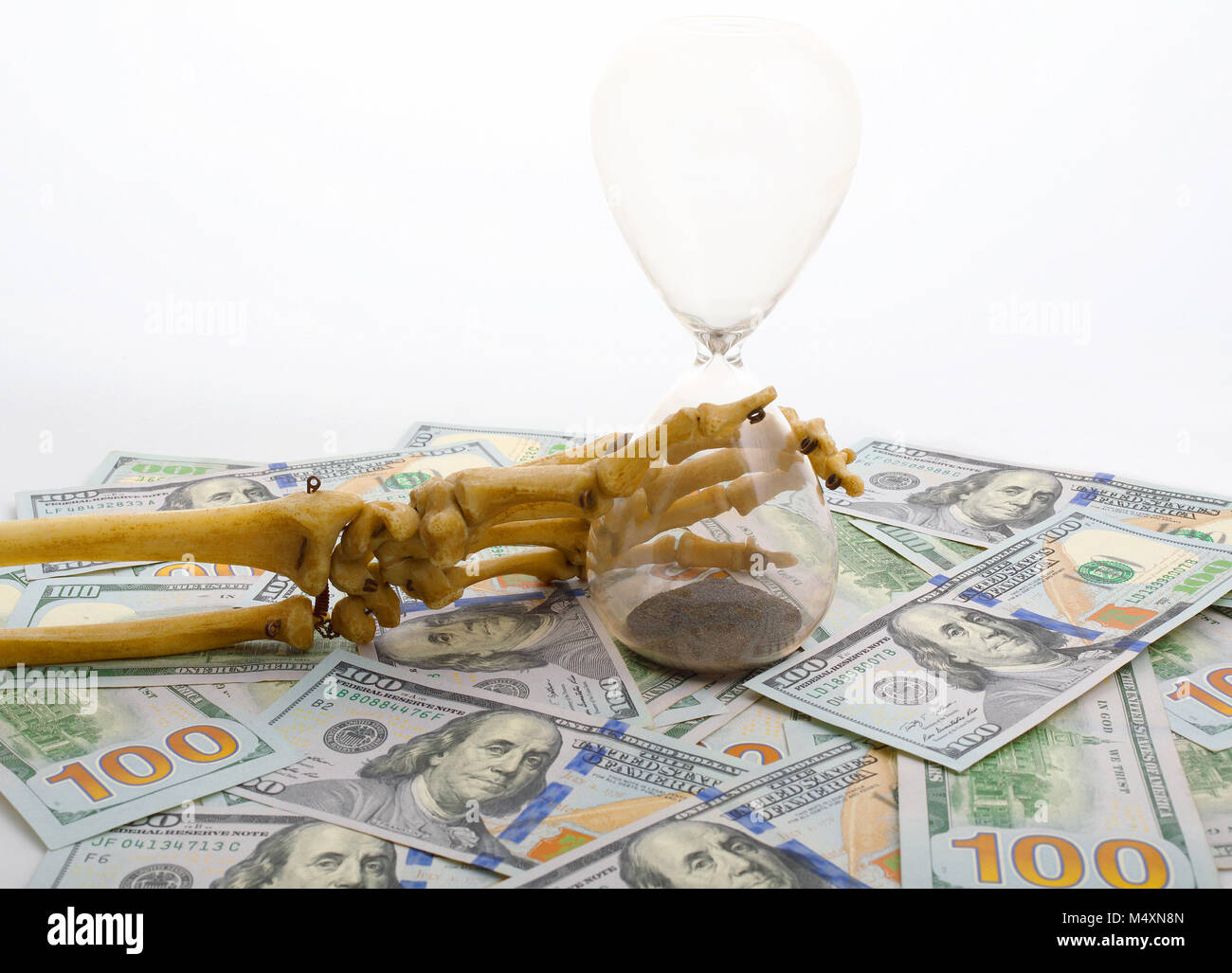 Dita di scheletro holding sabbia-vetro posto in dollari. concetto del tempo - il denaro e la morte. Foto Stock