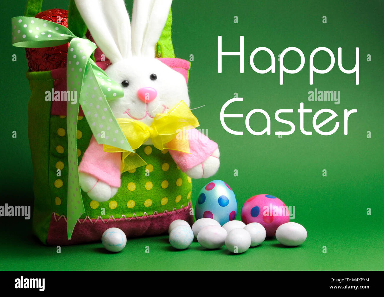 Felice Pasqua fatta in casa uovo di Pasqua Caccia colorato pois cestello carry bag e uova di pasqua di cioccolato su sfondo verde, con testo di saluto. Foto Stock