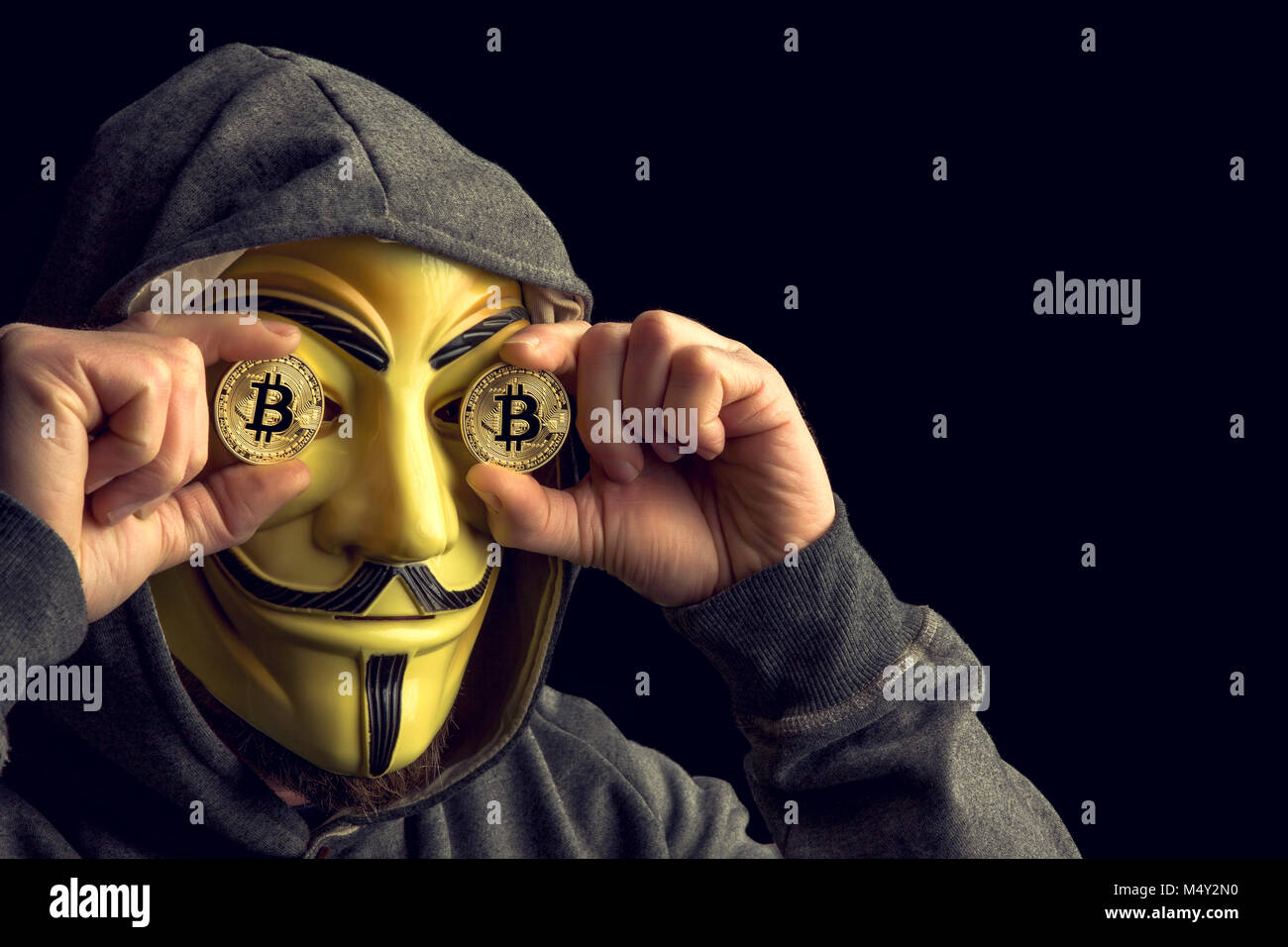 Milano,Italia, Febbraio 2018: Hacker vecchia moneta bitcoin e indossare maschera anonimi .foto editoriale. Foto Stock