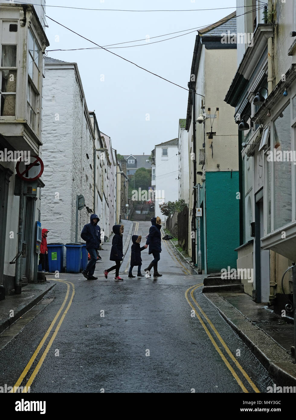 La gente a piedi attraverso una piovosa cittadina. Foto Stock