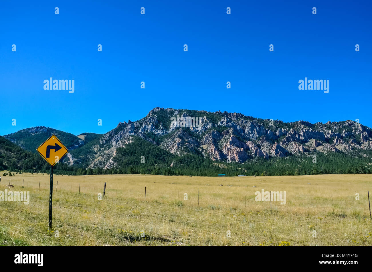 La svolta a destra segno posto nella parte anteriore del filo spinato con vista in lontananza Big Horn pedemontana sulla donna pazzesca strada in Wyoming. Foto Stock