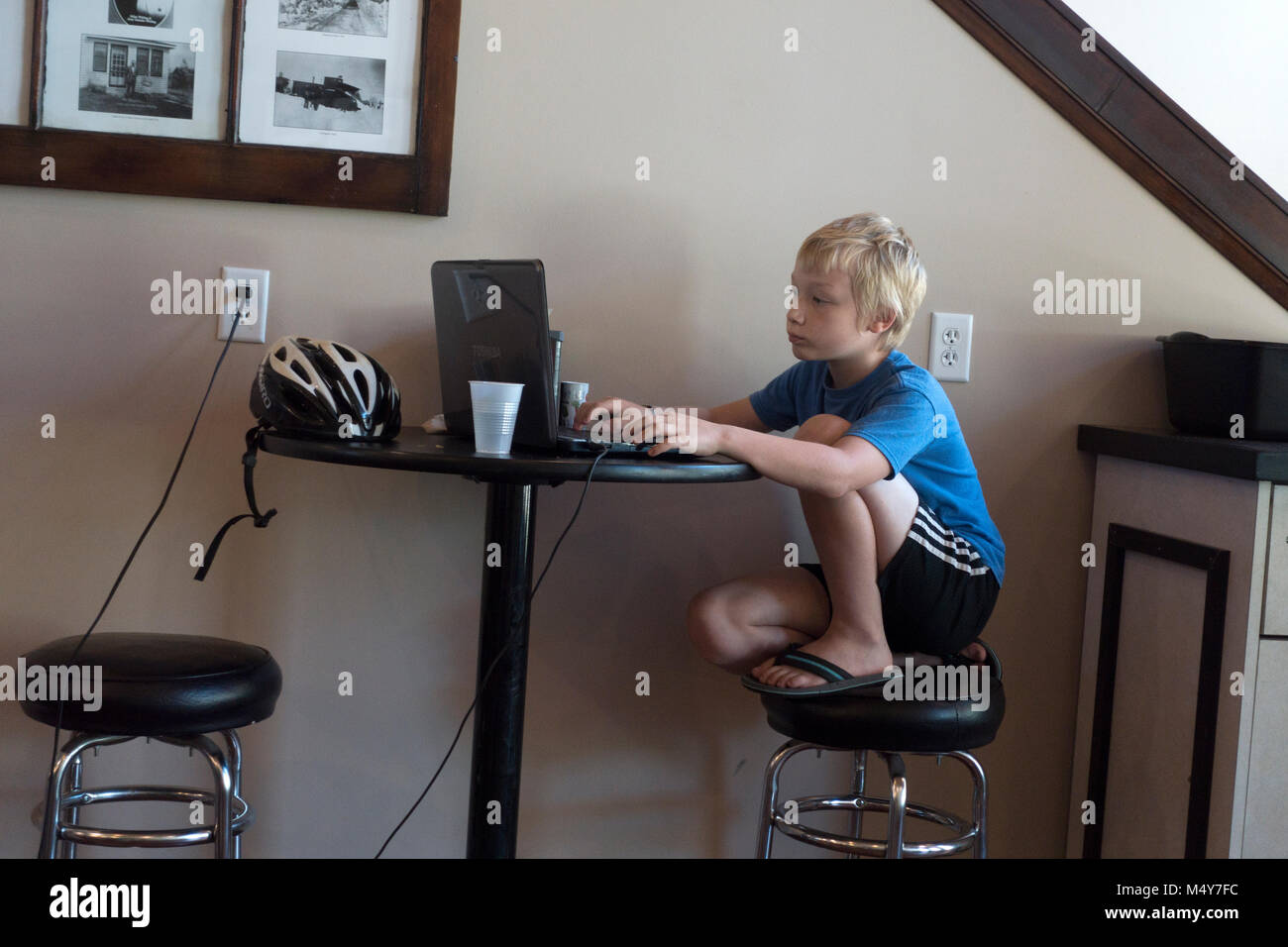 Ragazzo giovane età 10 assorbito come lavora sul suo computer presso un negozio di caffè tavola. Clitherall Minnesota MN USA Foto Stock