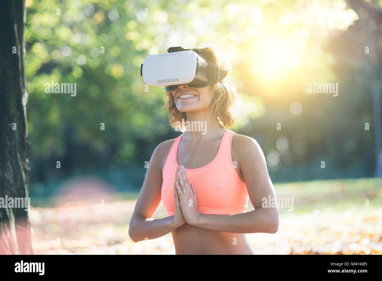 Giovane donna a praticare yoga nella natura con casco VR Foto Stock