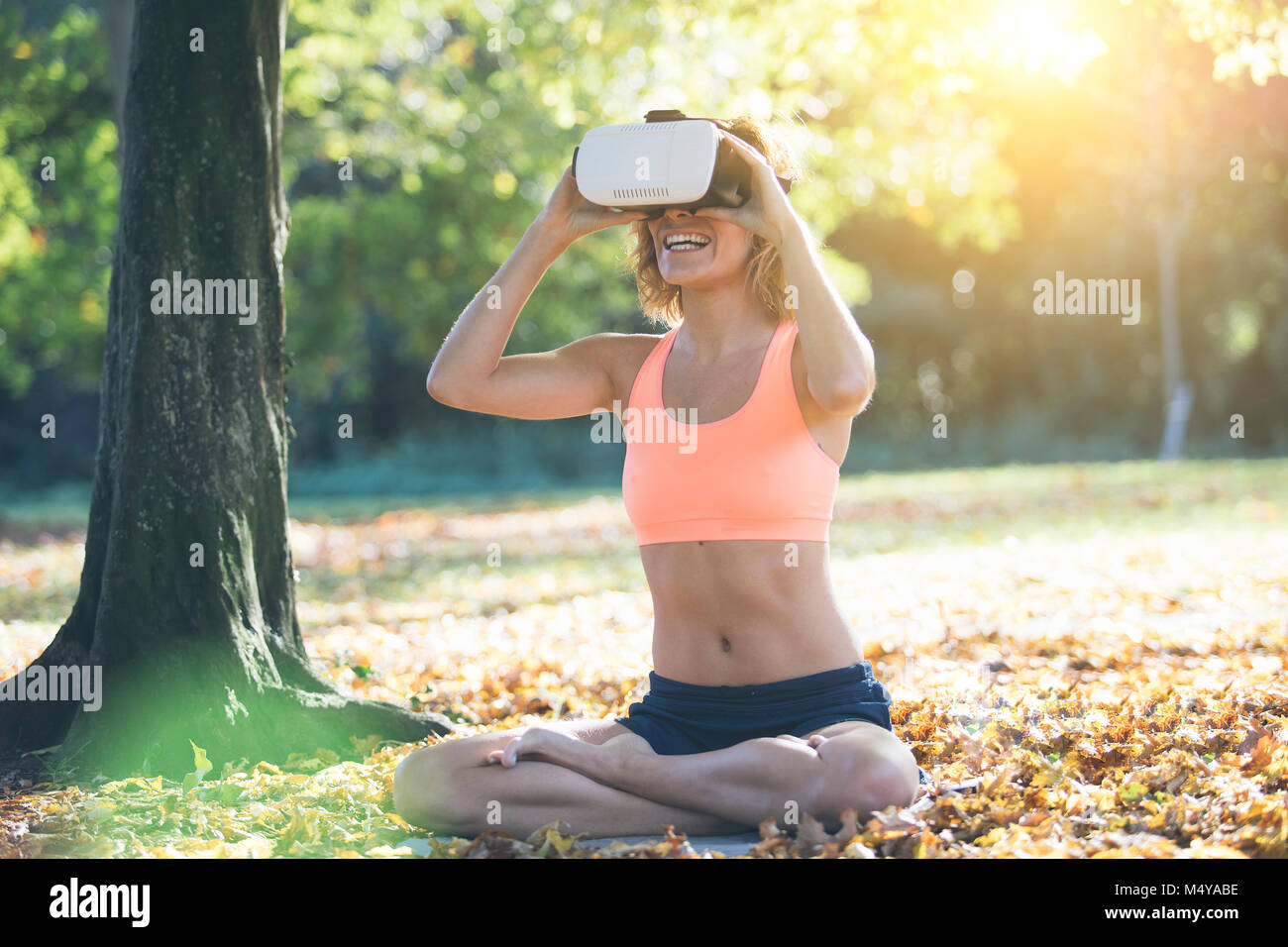 Giovane donna a praticare yoga nella natura con casco VR Foto Stock