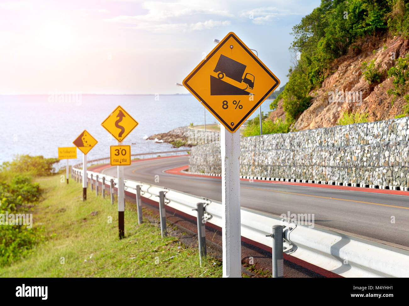 Il simbolo di avvertimento segno per protecion del traffico nella strada di montagna foto in sun illuminazione. Foto Stock