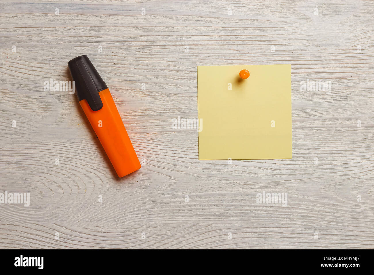 Fermo, fustellato adesivo giallo arancio e puntine, marcatore bianco sulla tavola di legno. Memo, promemoria. Foto Stock