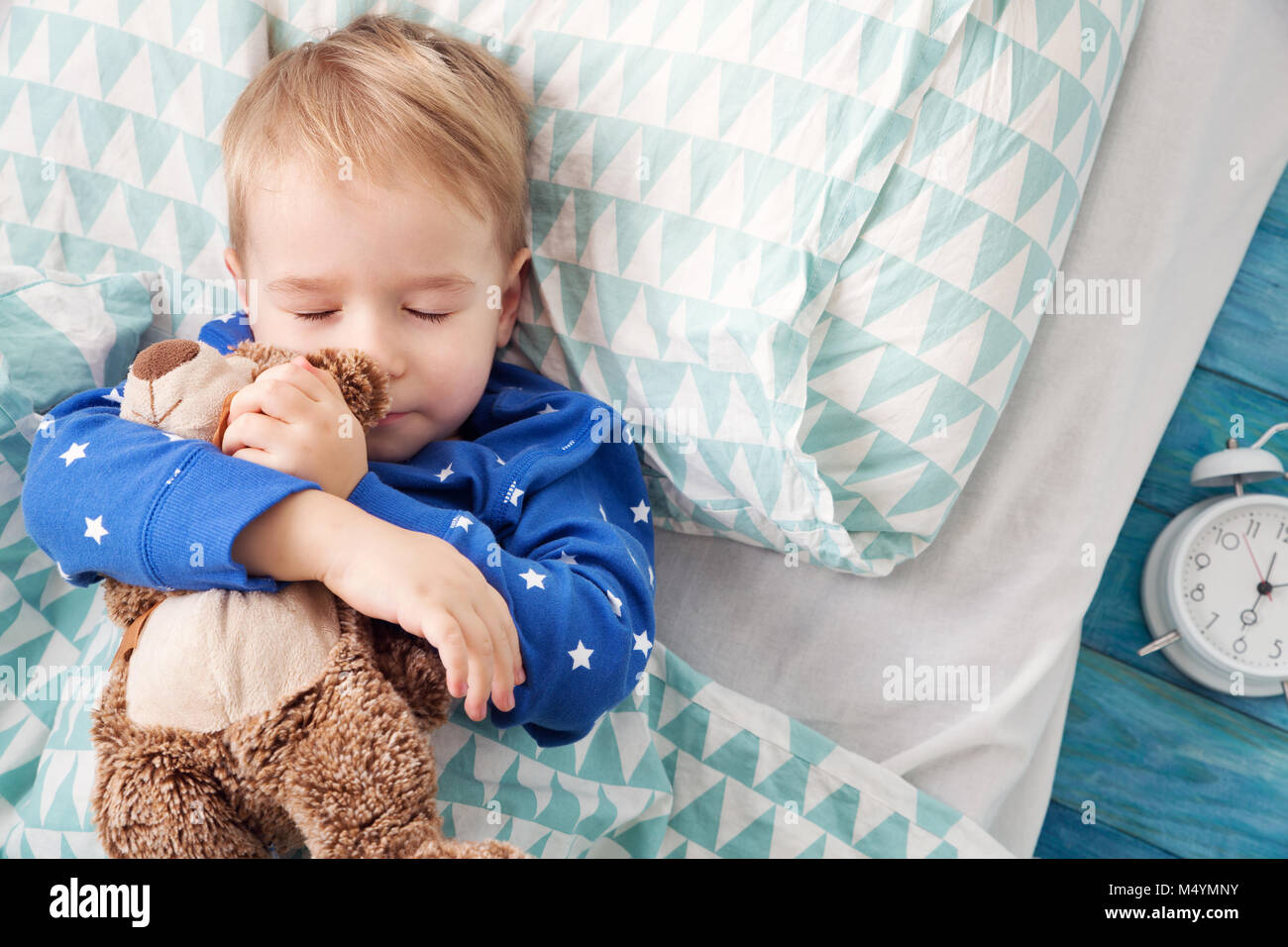 Tre anni bambino che dorme nel letto con la sveglia Foto stock - Alamy
