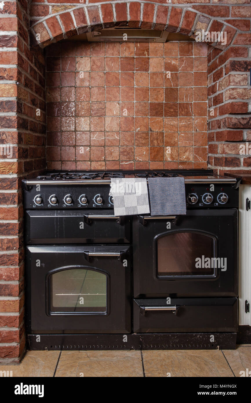 Termocucina in un rosso mattone cucina. Stufa e fornello. Foto Stock