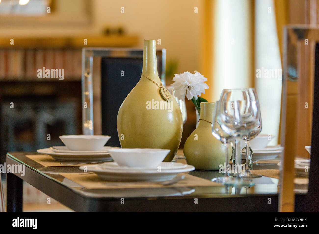 Primo piano di una messa in tavola con coppa, piatti, bicchieri da vino e vasi. Allestimento della casa. Interni. Foto Stock