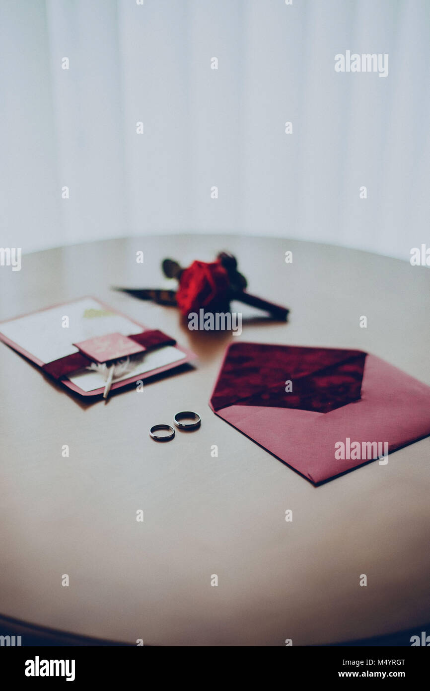 Busta boutonniere inviti gli anelli di nozze sulla tavola presso l'hotel Foto Stock