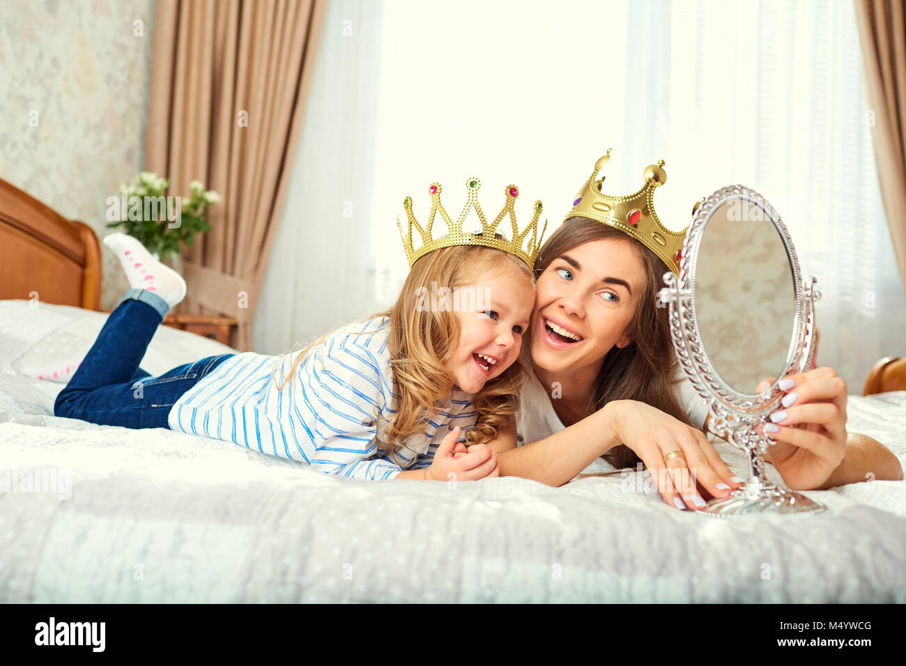 Madre e figlia con corone sulla testa sta giocando a b Foto Stock