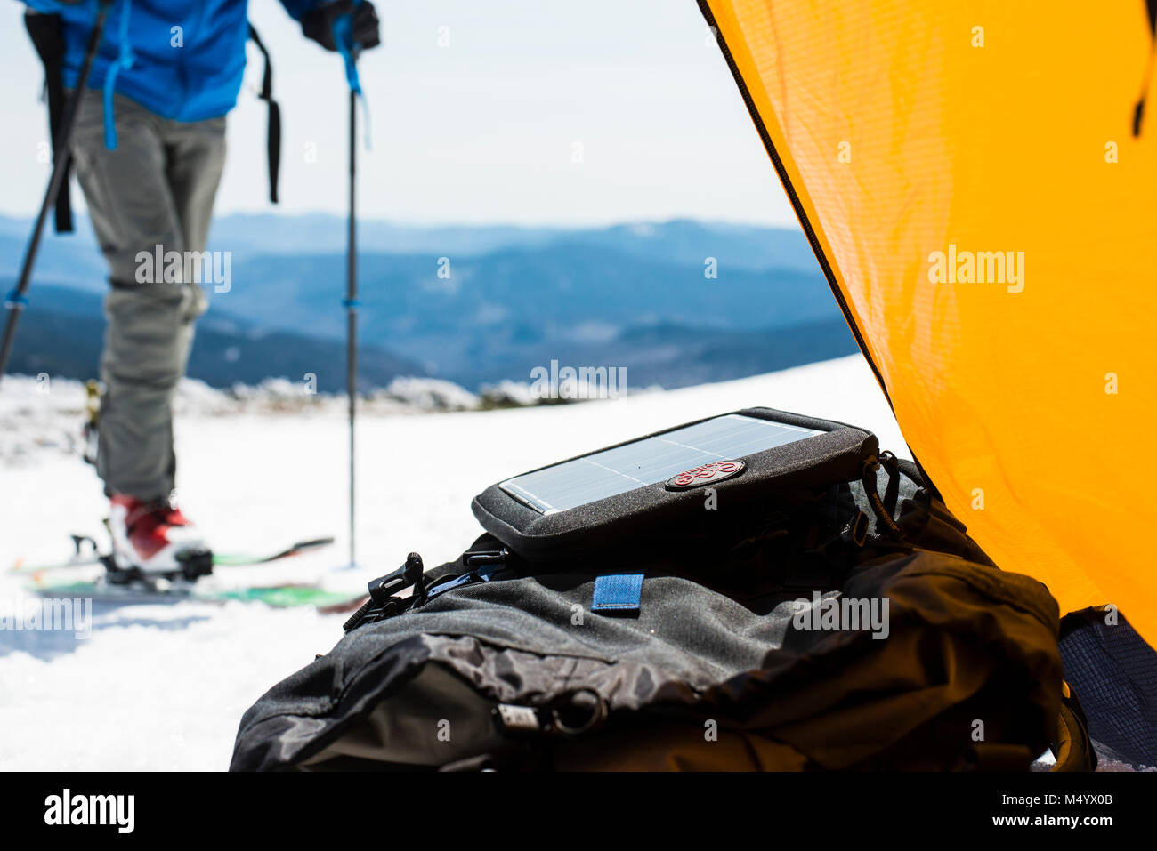 Sezione bassa di sciatore fuori tenda da campeggio con pannello solare in inverno nelle White Mountains, New Hampshire, STATI UNITI D'AMERICA Foto Stock