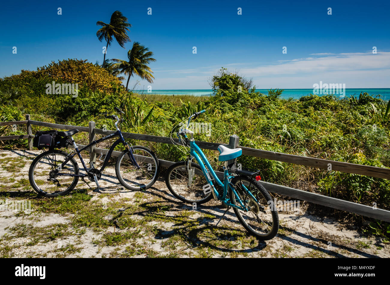 Due biciclette, uno con un sacco di sella, sedersi parcheggiata da una staccionata di legno sulla spiaggia di Bahia Honda State Park in Florida Keys. Foto Stock
