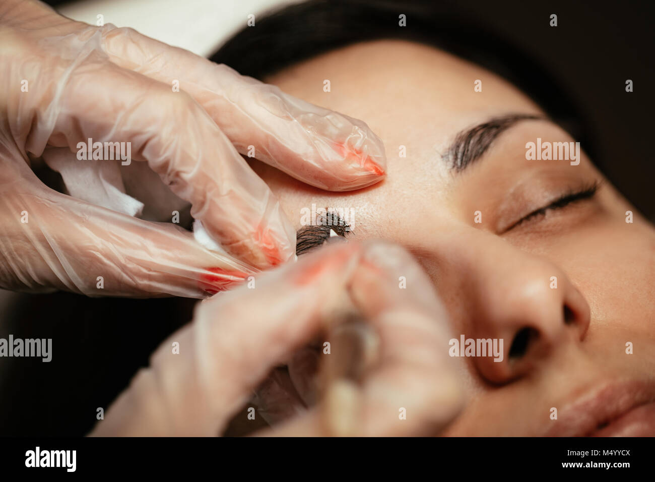 Close-up di una estetista mani microblading sopracciglia al modello. Foto Stock