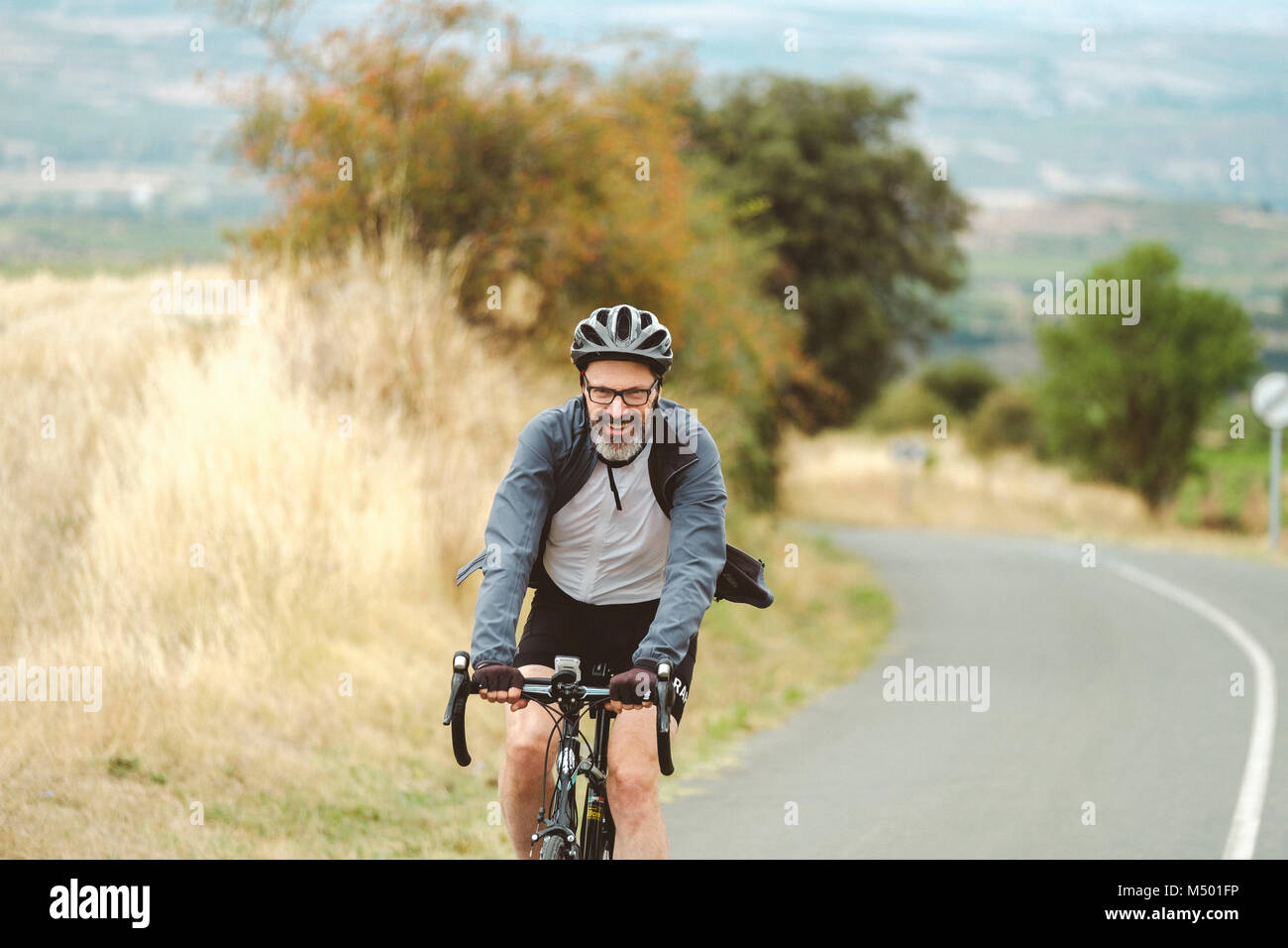 Di mezza età ciclista pedala in bici su strada, Pamplona, Navarra, Spagna Foto Stock