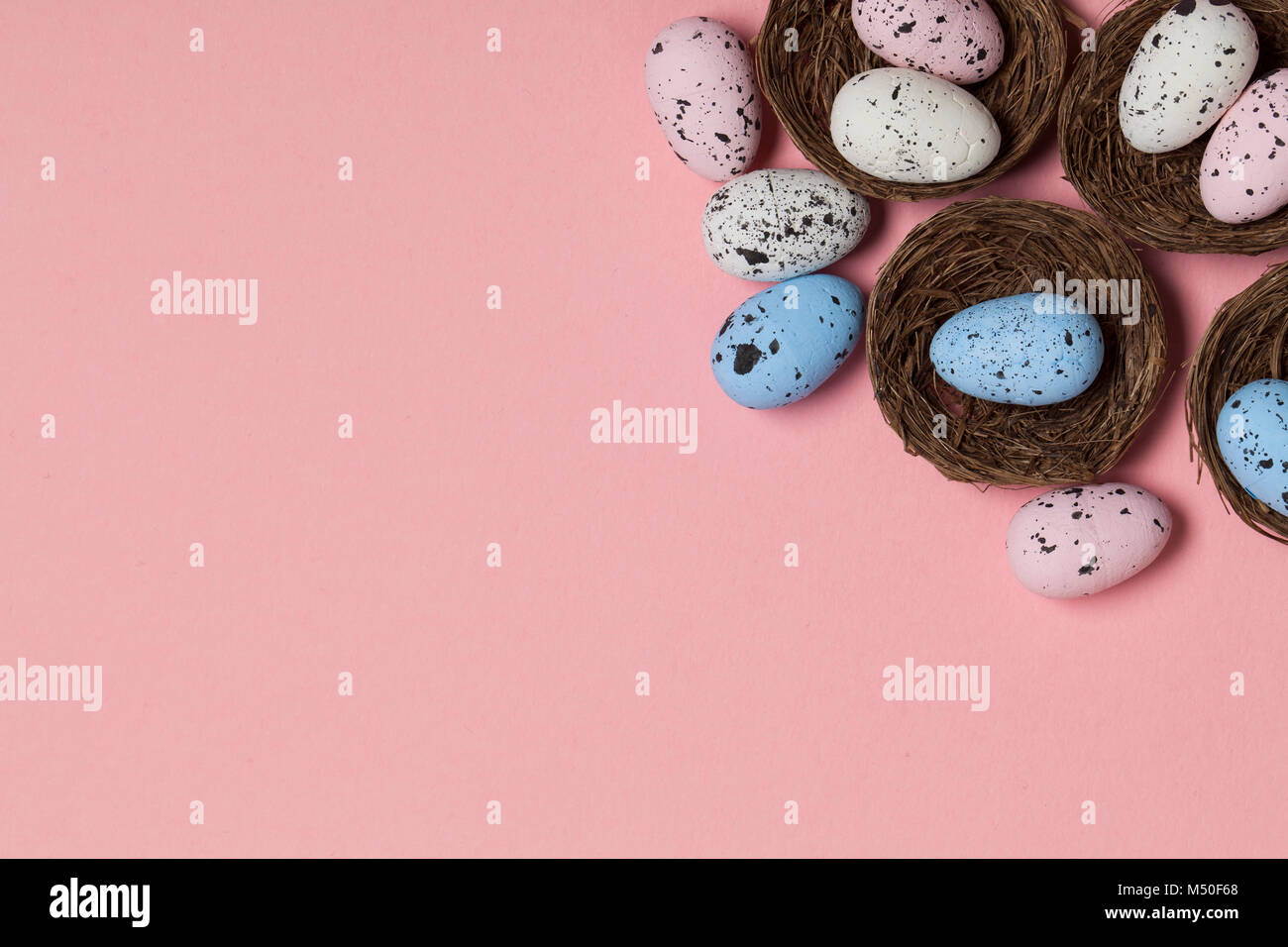 Uova di Pasqua in un nido su un pastello sfondo rosa Foto Stock