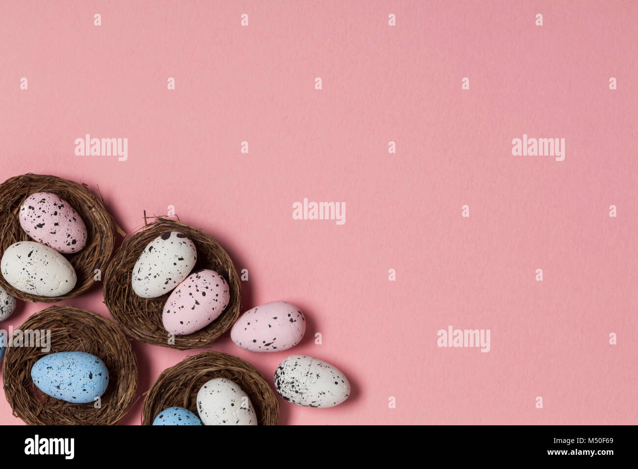 Uova di Pasqua in un nido su un pastello sfondo rosa Foto Stock