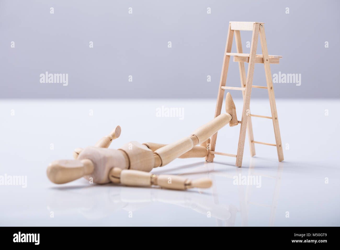 Figura in legno sdraiato sul pavimento dopo la caduta dalla scaletta Foto Stock