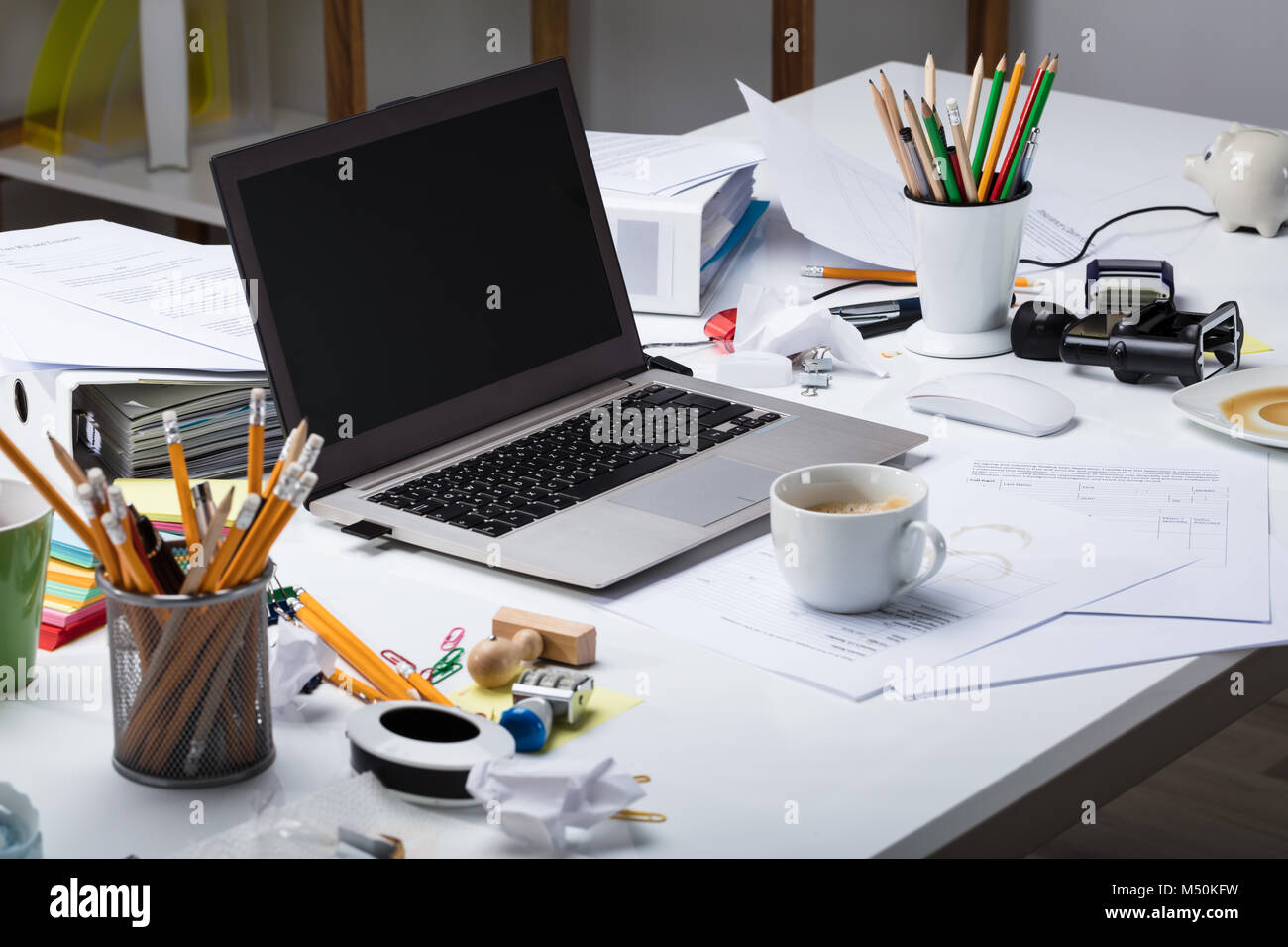Laptop e la tazza di caffè sul documento carta sopra il disordine scrivania in ufficio Foto Stock