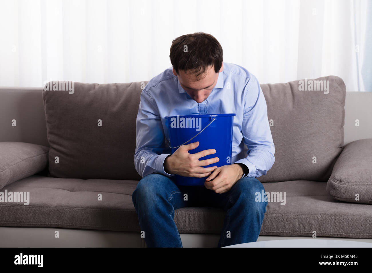 Un uomo seduto sul divano vomito in sacchetto di carta a casa Foto stock -  Alamy