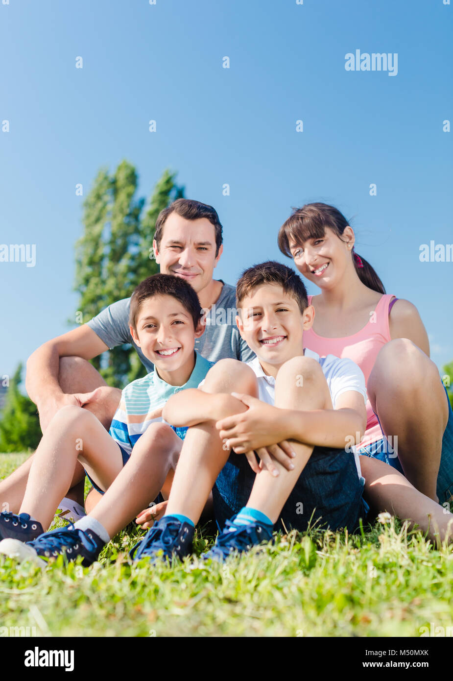 Famiglia vestita di bianco nel parco in estate seduta in Prato Foto Stock