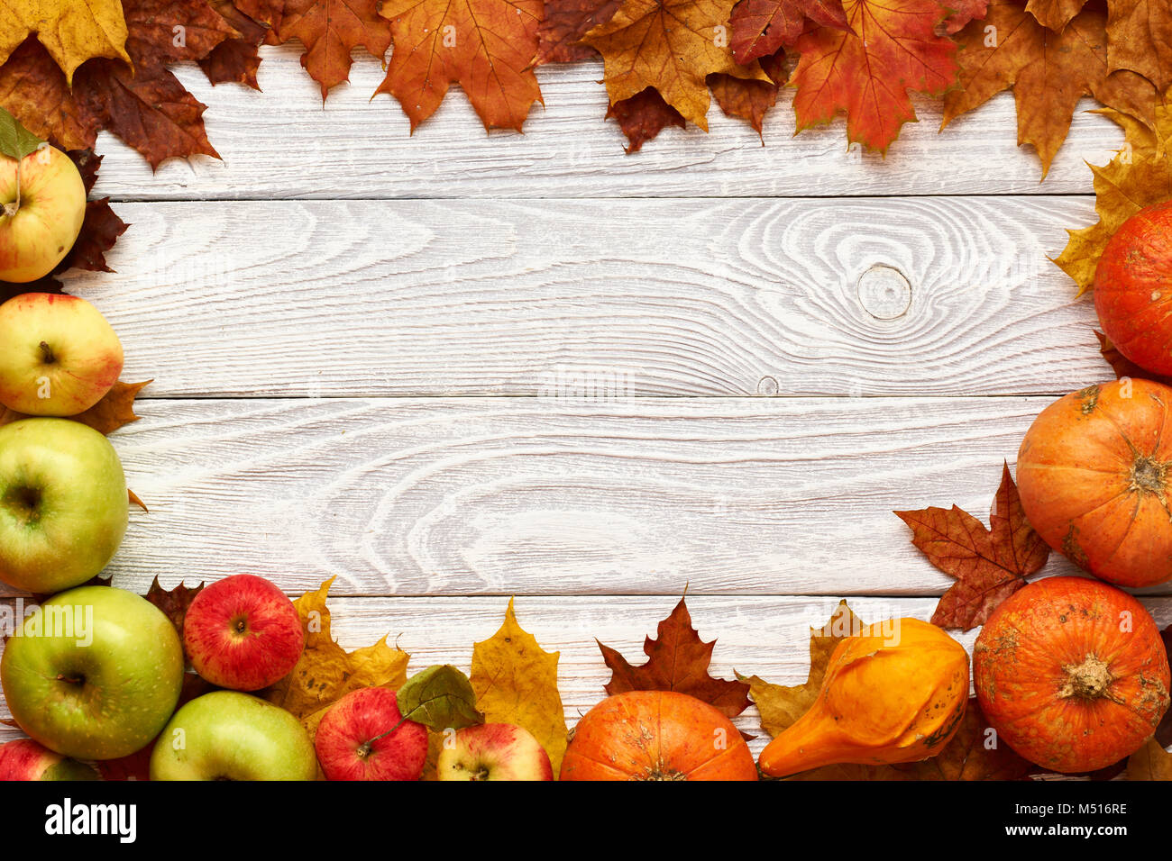 Foglie di autunno, mele e zucche su sfondo di legno Foto Stock